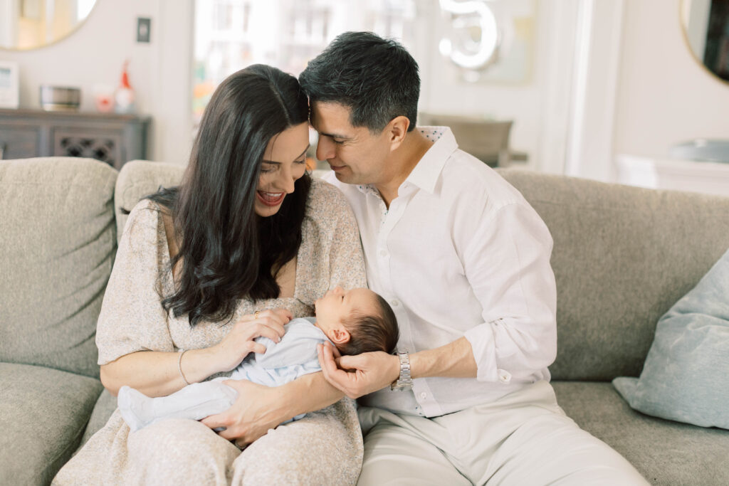 dad kissing mom while holding newborn