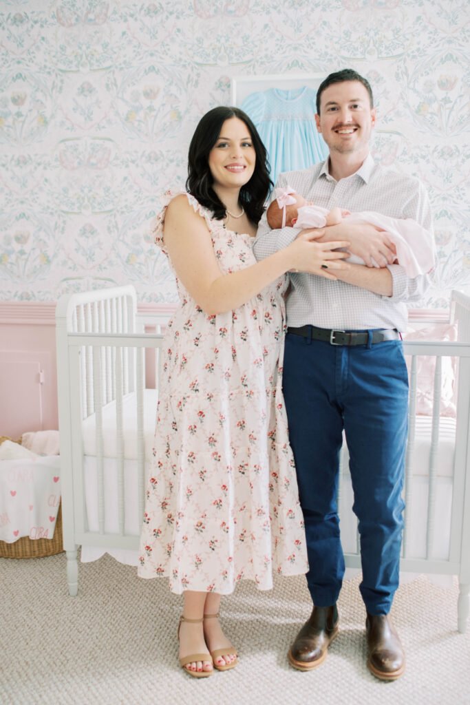 mom and dad cradling newborn baby girl in her nursery 
