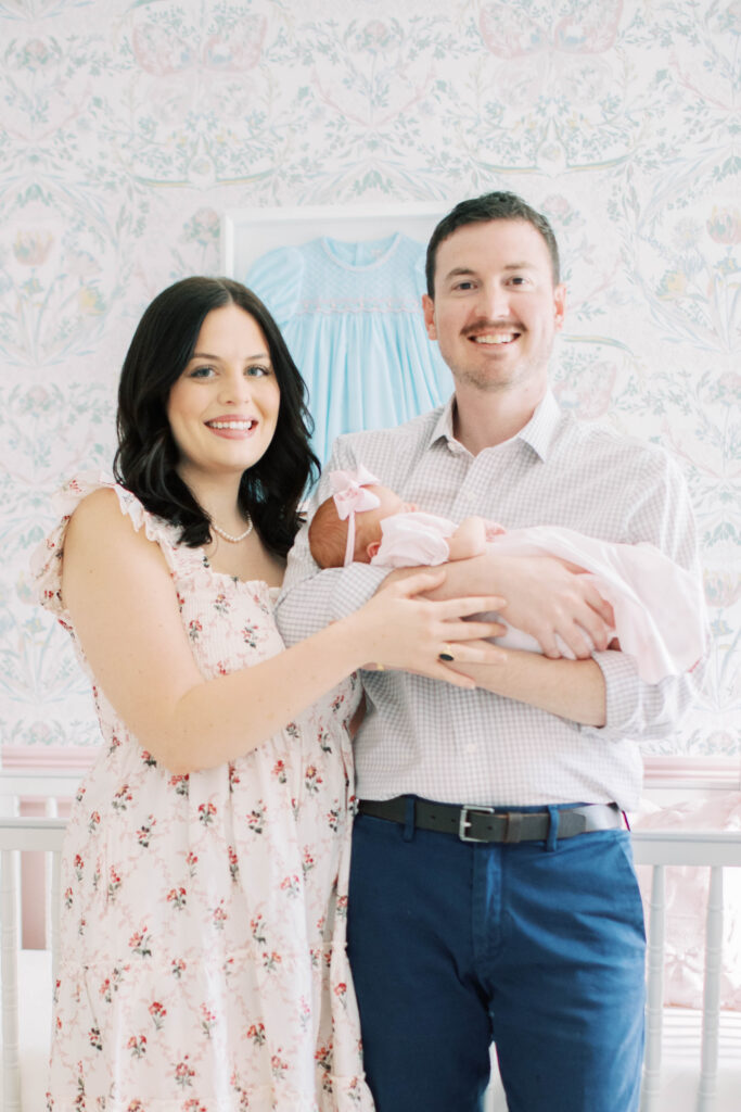 mom and dad cradling newborn baby girl in her nursery 