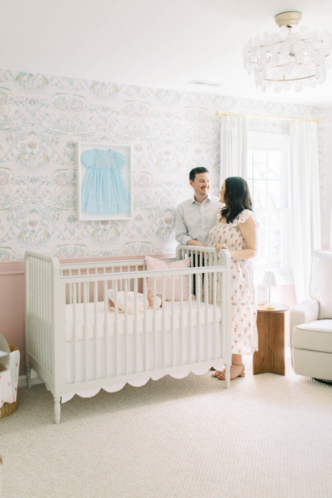 mom and dad looking over crib at their newborn baby girl in her nursery 