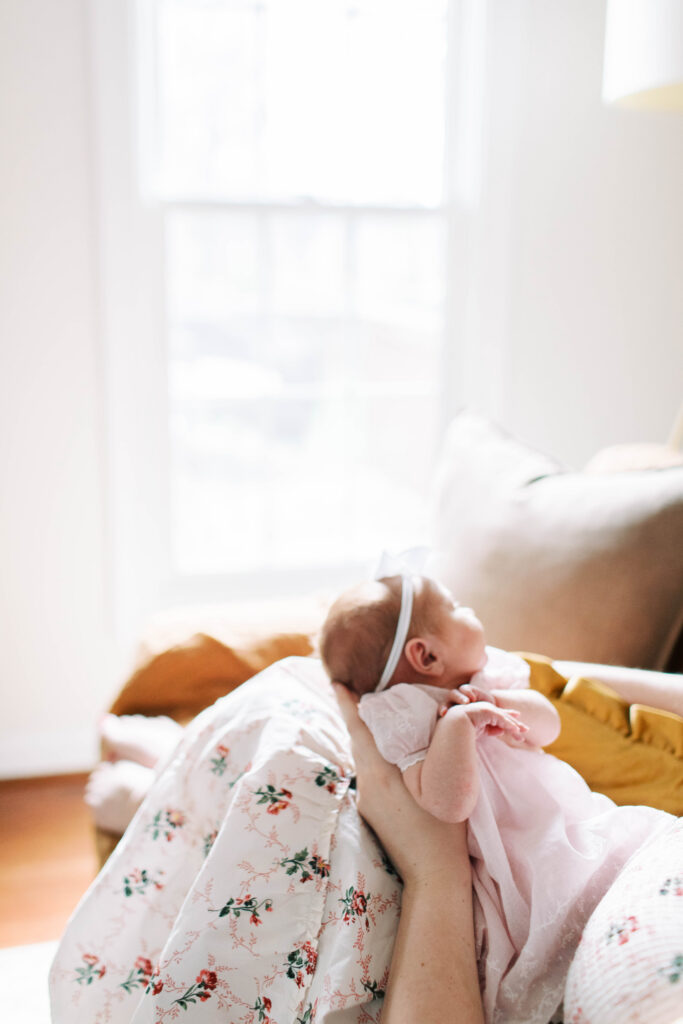 mom holding newborn baby girl on the couch in living room 