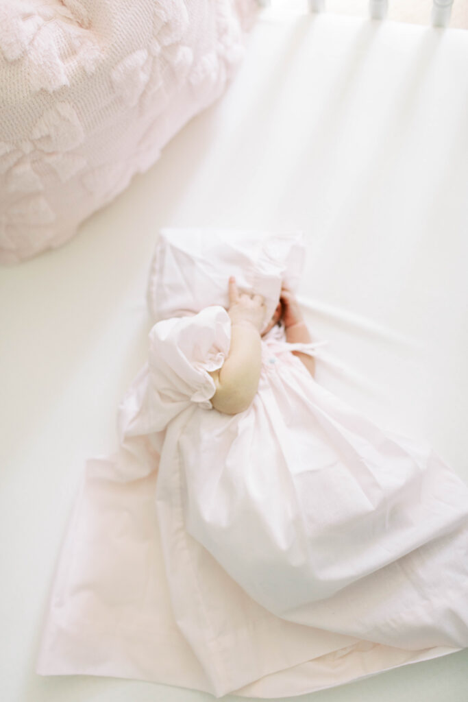 newborn in crib in traditional dress and bonnet 