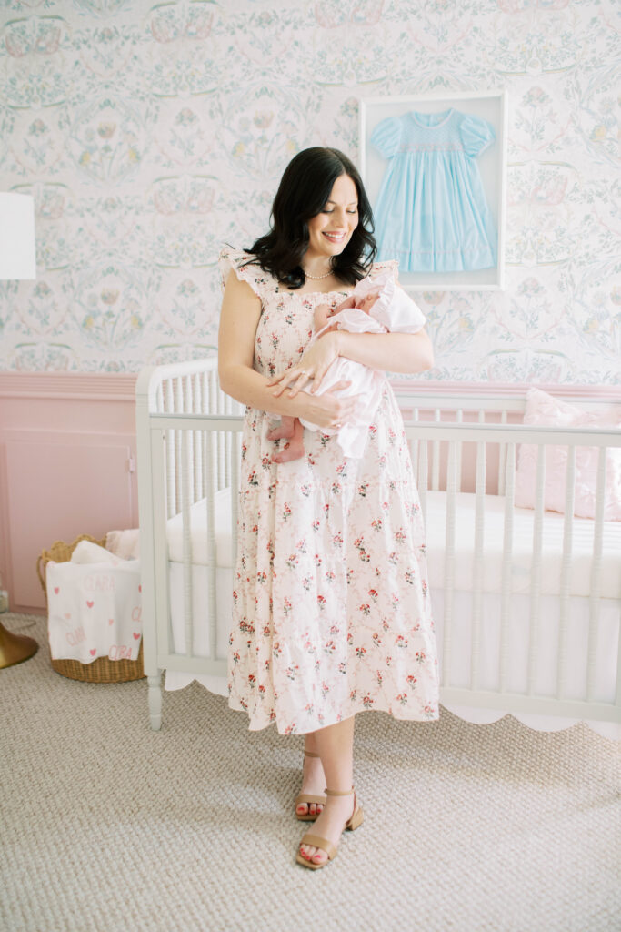 mom in floral flowy hill house dress holding newborn baby girl 
