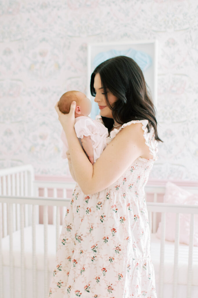 mom in floral flowy hill house dress holding newborn baby girl face to face
