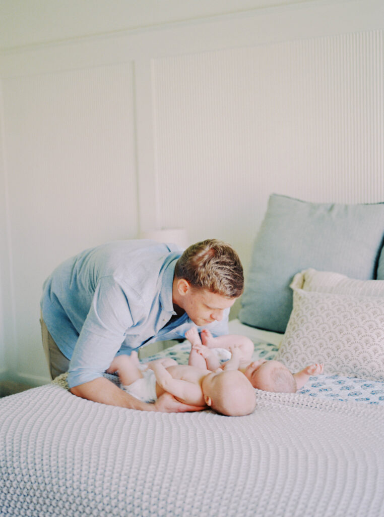 dad playing with twin boys on bed 