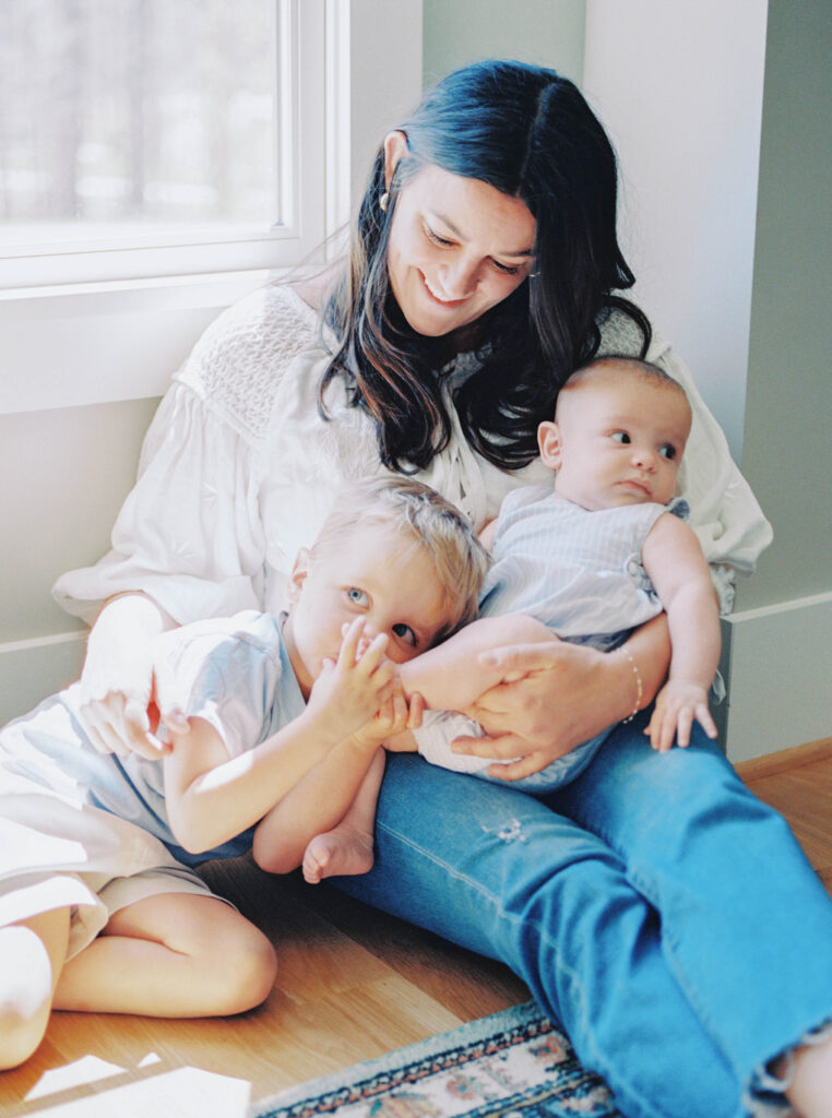 mom snuggled by window with kids 