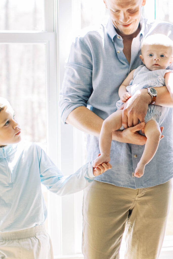 dad holding baby by window