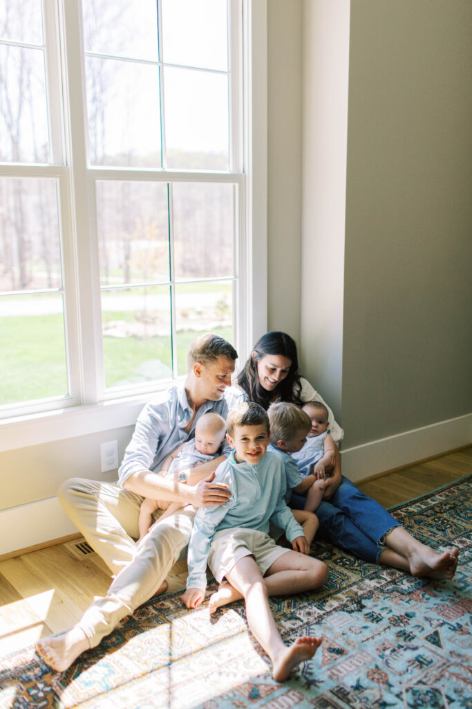 parents snuggled up with kids inside by window