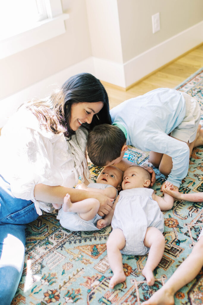 babies laying on ground with mom and big brother snuggling 