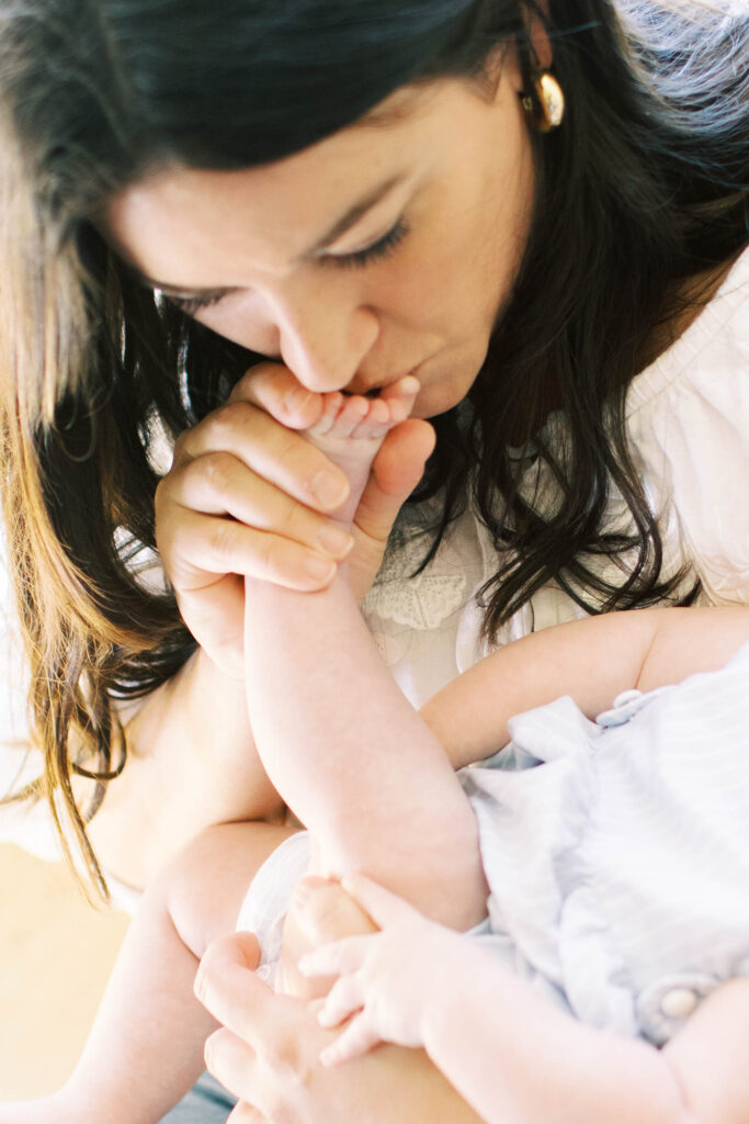 mom kissing infant foot