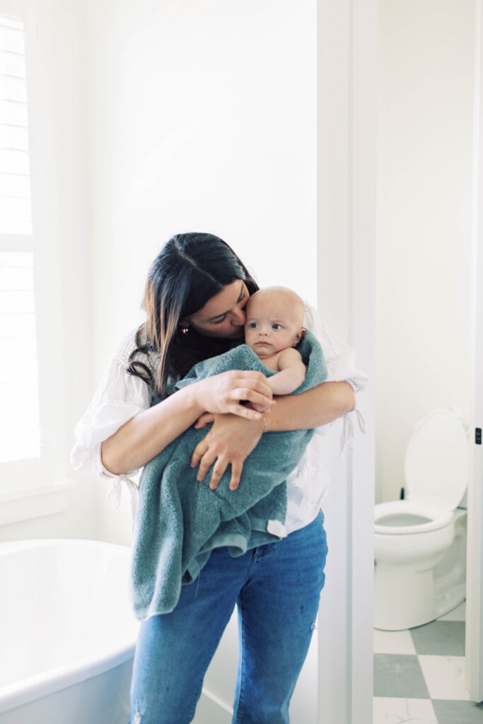 mom snuggling baby in towel after bath 