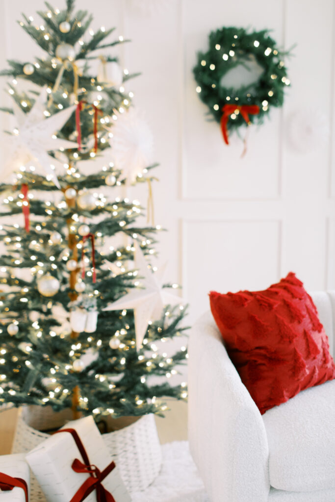 white couch in a studio thats decorated for christmas  with a wreath and christmas tree in the background